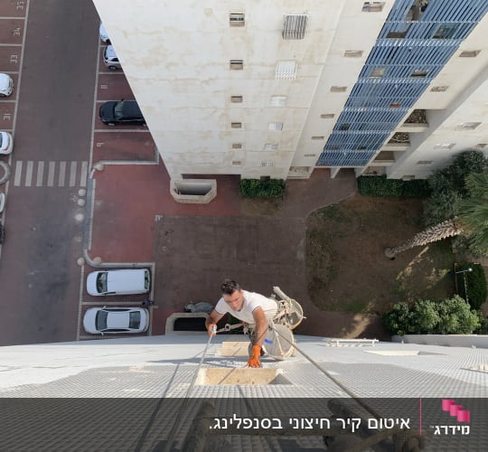 אדם מטפס על קיר בניין גבוה עם חבלים